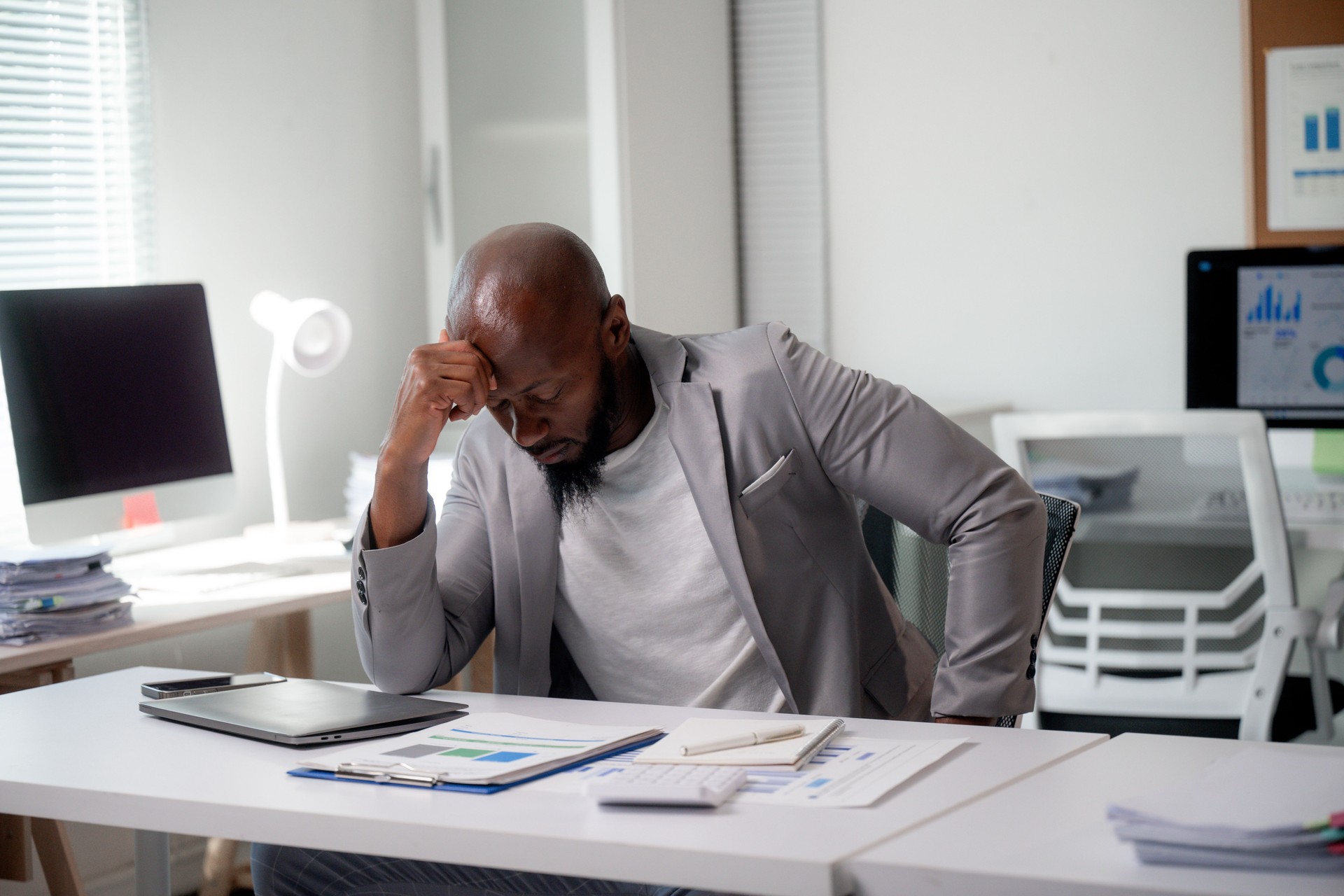 Small business owner thoughtfully reviewing resumes on a laptop, reflecting the challenges of hiring the right candidate
